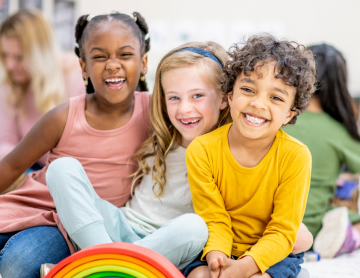 Three children sitting and smiling.
