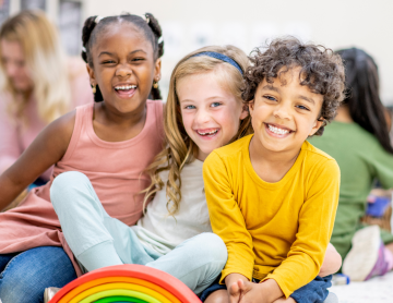 Three children sitting and smiling. 