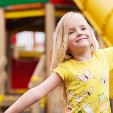 little girl in front of playground equipment