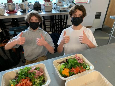 Two students show off their meal with a thumbs up