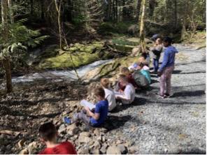 Students sit outside in a line and do school work