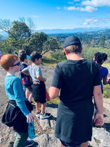 Students stand on a lookout point and look out over mountains.