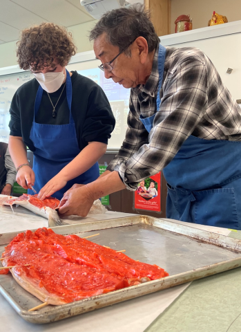 A student and a teacher prepare to bake salmon